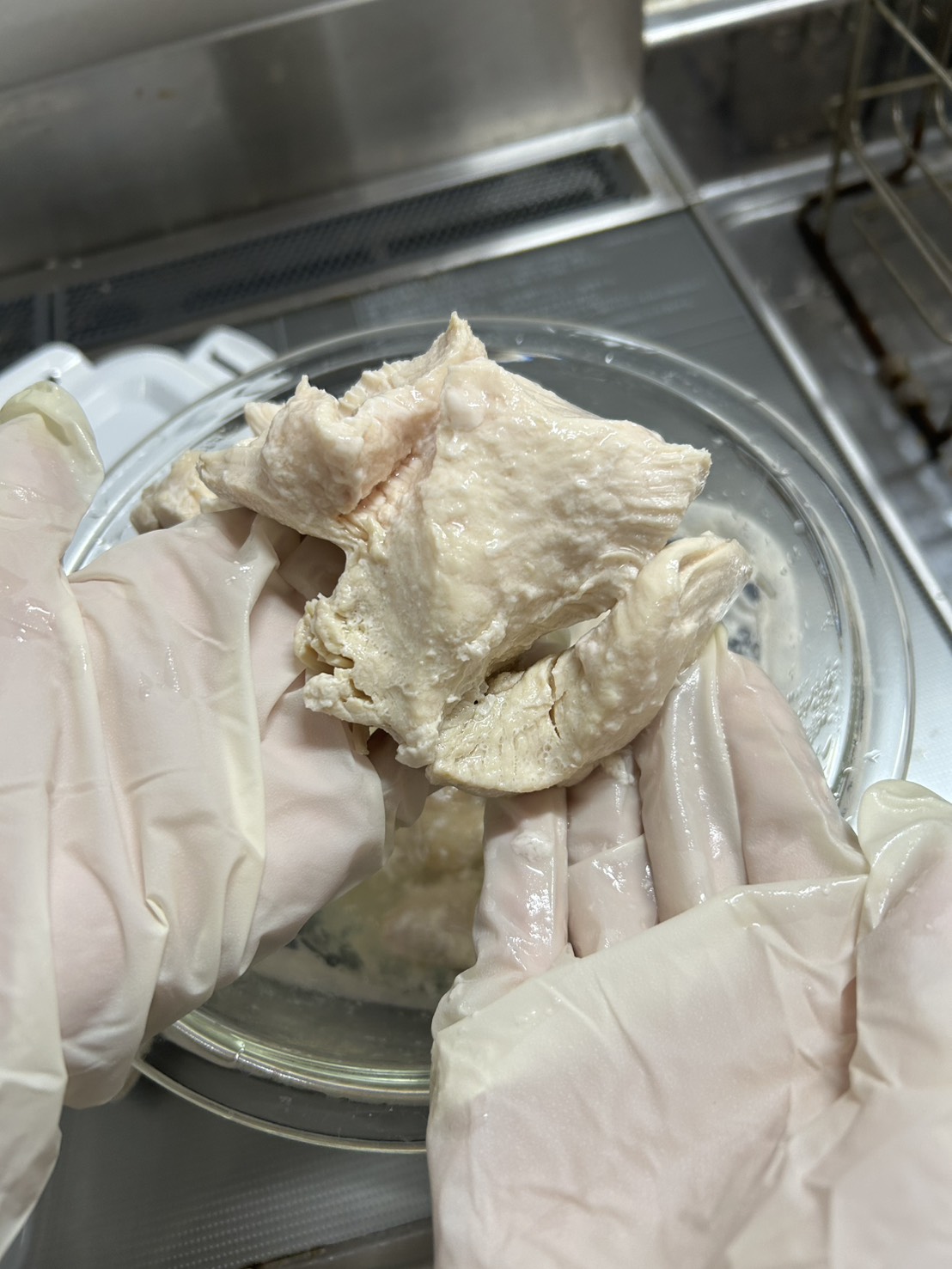 加熱後の鶏むね肉を手で裂いている様子